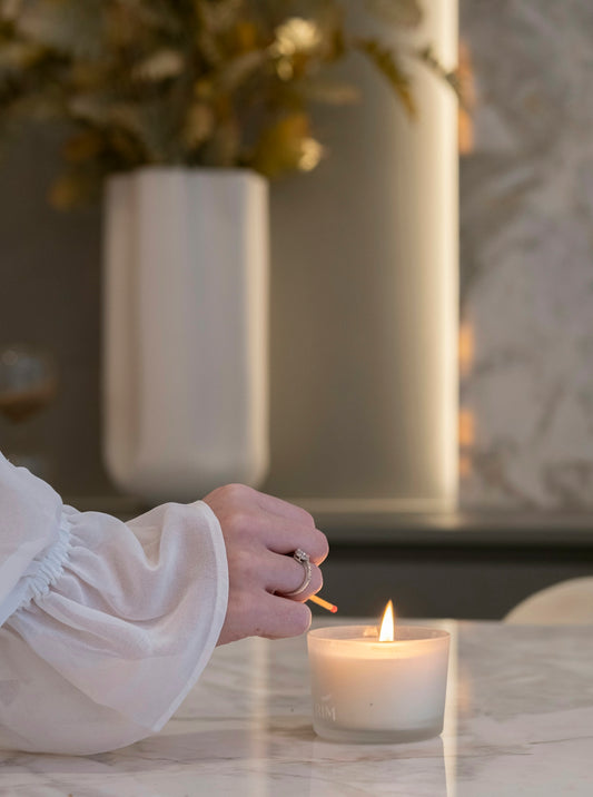 Hand lighting a candle on a marble table.