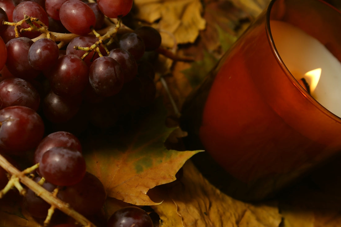 Grapes and a lit candle on autumn leaves