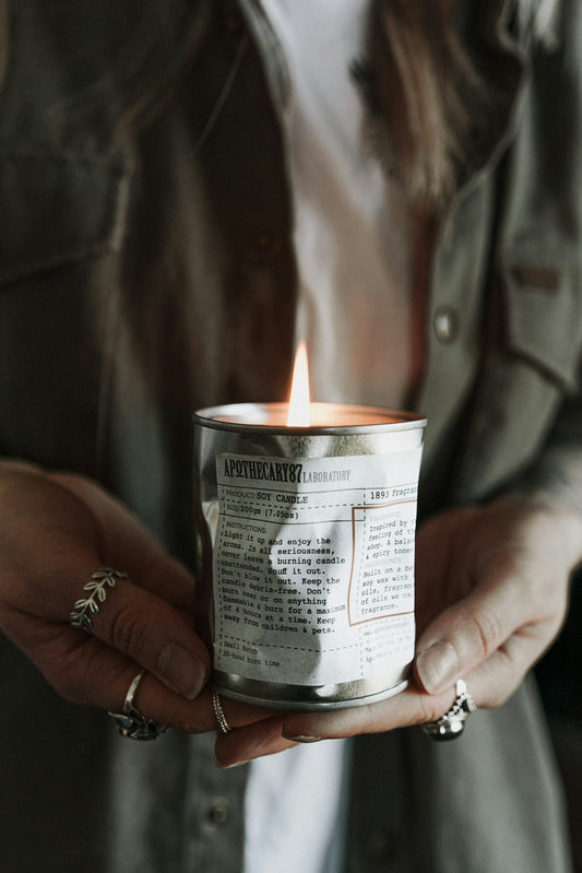 Person holding a lit candle in a tin can.
