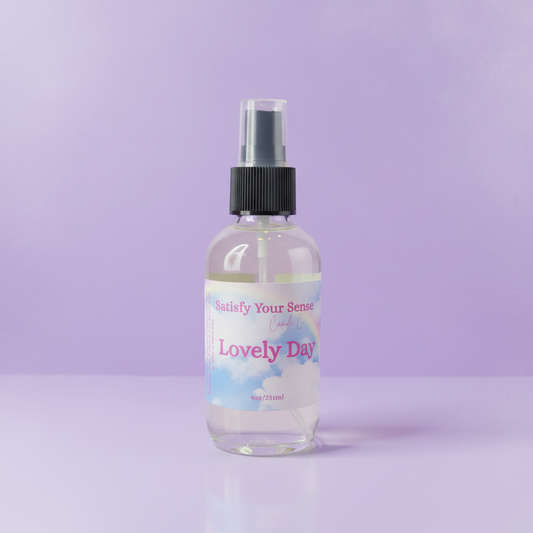 A clear bottle of "Lovely Day" aroma room spray with a rainbow and cloud label.